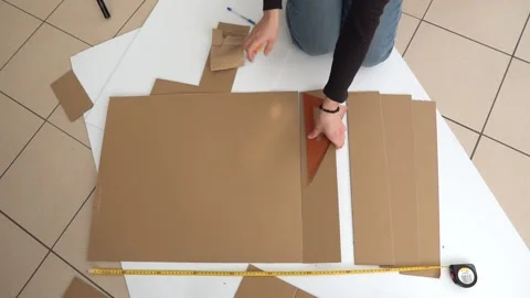A man cuts a sheet of cardboard into strips Stock Footage 142931616