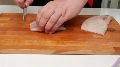 A man cuts a squid fillet with a knife on a wooden kitchen board, hands, clos Video stock 132285509