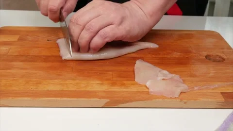 A man cuts a squid fillet with a knife on a wooden kitchen board, hands, clos 動画素材 132285565
