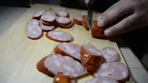 Man cuts into thin slices fatty sausage. Shooting closeup. Chef cutting salami w Видео 128621487