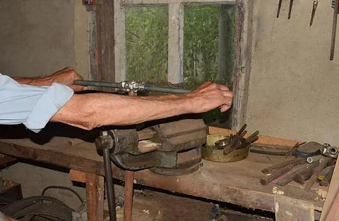 A man cuts a thread on a pipe with a hand thread chaser and a vise. Foto stock
