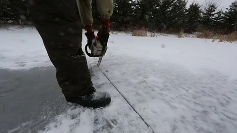 Man cuts through ice with chainsaw close Stock Footage 77280622