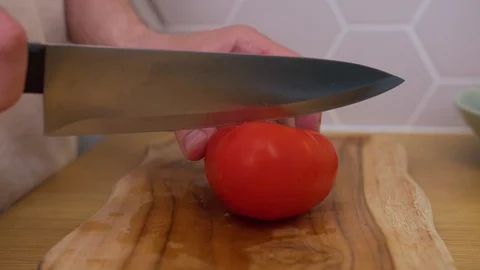 A man cuts a tomato on a chopping Board Stock Footage 129056689