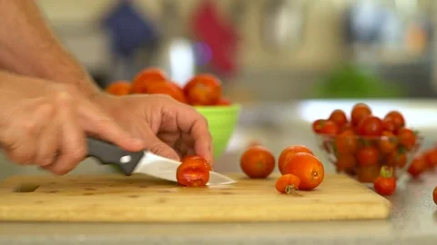 Man cuts tomato on cutting board Видео 77327175