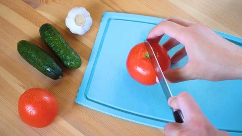 A man cuts tomatoes and cucumbers to make a salad 4K UHD Video stock 96886484