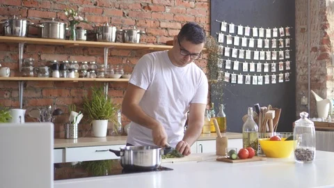 Man cuts vegetables in the kitchen and experiences a sharp headache, he grabs Stock Footage 98312458