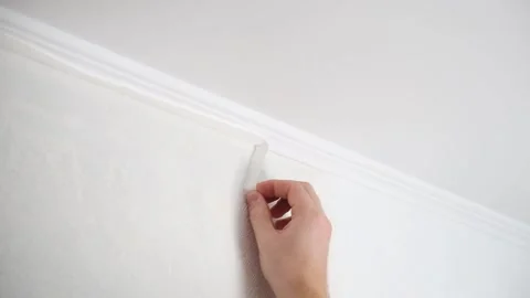 Man cuts wallpaper near ceiling moldings using box cutter and putty blade Stock Footage 201320677