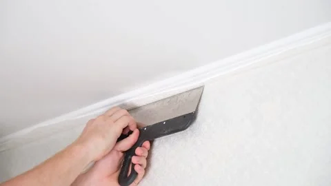 Man cuts wallpaper near ceiling moldings using box cutter and putty blade Stock Footage 201320697