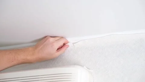 Man cuts wallpaper near ceiling moldings using box cutter and putty blade Stock Footage 201517425