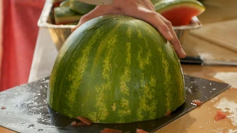Man cuts watermelon half into large wedges Stock Footage 94220669