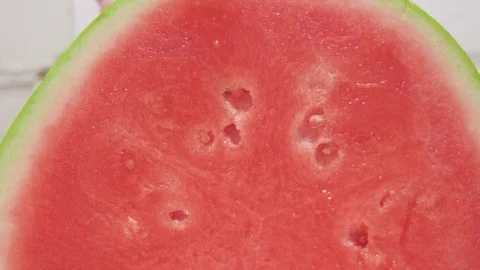Man Cuts a Watermelon in Half as Natural Light Fills the Kitchen Stock Footage 79051499