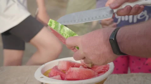A man cuts a watermelon with a large knife into a plate. Stock Footage 142188747