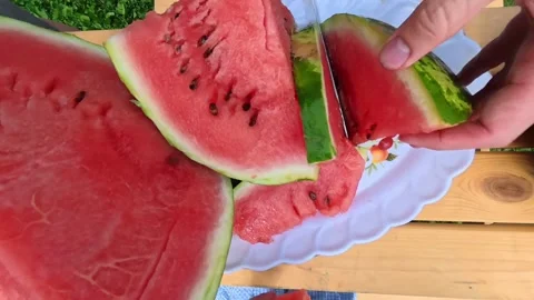 A man cuts a watermelon outside. Stock Footage 314400000
