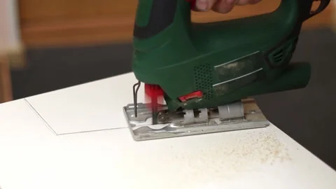 A man cuts a window sill from board for a window using an electric jigsaw for Stock Footage 165915166