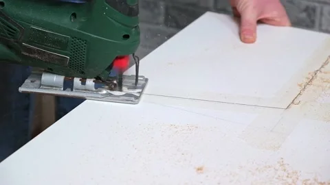 A man cuts a window sill from board for a window using an electric jigsaw for Vídeo Stock 168217659