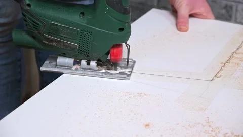 A man cuts a window sill from board for a window using an electric jigsaw for Stock Footage 168648380