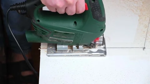 A man cuts a window sill from board for a window using an electric jigsaw for Видео 169110661