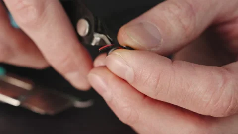 Man cuts wire with wire cutters on wooden table in close-up Stock Footage 237145504