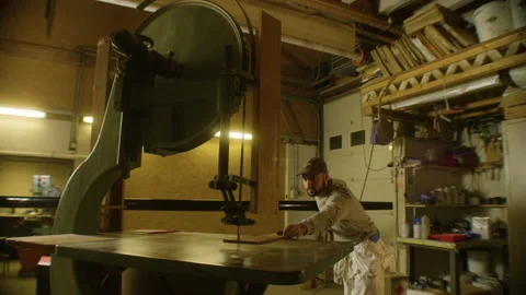 A man cuts wood with an electric machine that saws wood in a workshop Stock Footage 229746318