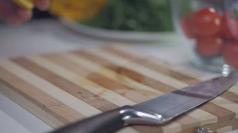 A man cuts a yellow pepper with a knife on a divided board. Stock Footage 103444677