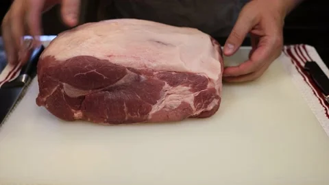 Man Cutting and trimming Large Pork Meat In A Kitchen With Two Knives Stock Footage 140552282