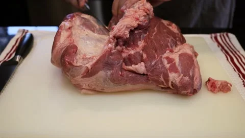Man Cutting and trimming Large Pork Meat In A Kitchen With Two Knives Stock Footage 140553302