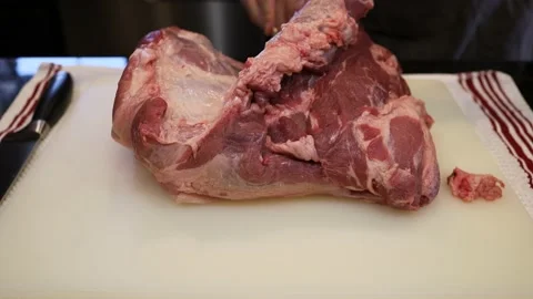 Man Cutting and trimming Large Pork Meat In A Kitchen With Two Knives Stock Footage 140553322