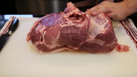 Man Cutting and trimming Large Pork Meat In A Kitchen With Two Knives Stock Footage 140553335