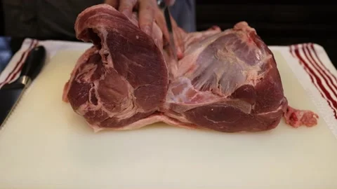 Man Cutting and trimming Large Pork Meat In A Kitchen With Two Knives Video stock 140553336