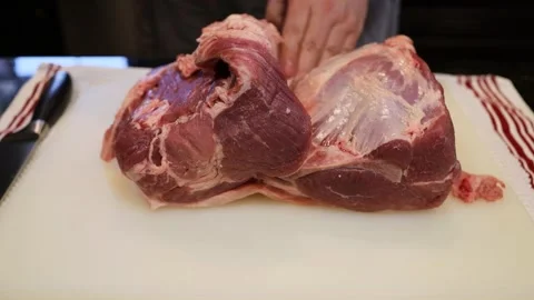 Man Cutting and trimming Large Pork Meat In A Kitchen With Two Knives Video stock 140553695