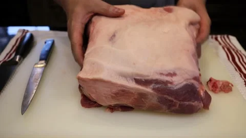 Man Cutting and trimming Large Pork Meat In A Kitchen With Two Knives Stock Footage 140553732