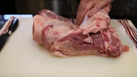 Man Cutting and trimming Large Pork Meat In A Kitchen With Two Knives Stock Footage 140553735