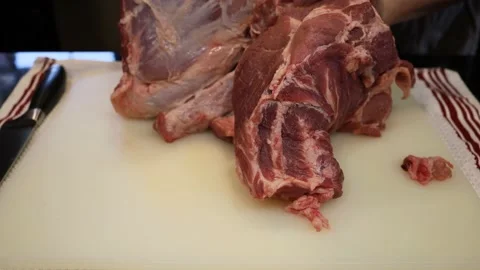 Man Cutting and trimming Large Pork Meat In A Kitchen With Two Knives Stock Footage 140554032