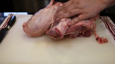 Man Cutting and trimming Large Pork Meat In A Kitchen With Two Knives Stock Footage 140554065