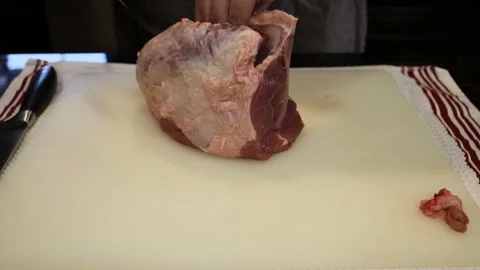 Man Cutting and trimming Large Pork Meat In A Kitchen With Two Knives Stock Footage 140555100