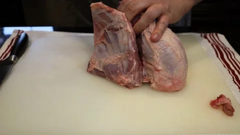 Man Cutting and trimming Large Pork Meat In A Kitchen With Two Knives Stock Footage 140555146