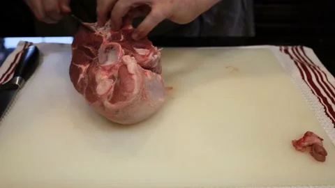Man Cutting and trimming Large Pork Meat In A Kitchen With Two Knives Stock Footage 140555330