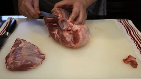 Man Cutting and trimming Large Pork Meat In A Kitchen With Two Knives Stock Footage 140555716