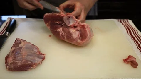 Man Cutting and trimming Large Pork Meat In A Kitchen With Two Knives Stock Footage 140555717