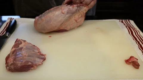 Man Cutting and trimming Large Pork Meat In A Kitchen With Two Knives Stock Footage 140555989