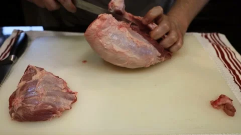 Man Cutting and trimming Large Pork Meat In A Kitchen With Two Knives Video stock 140556016