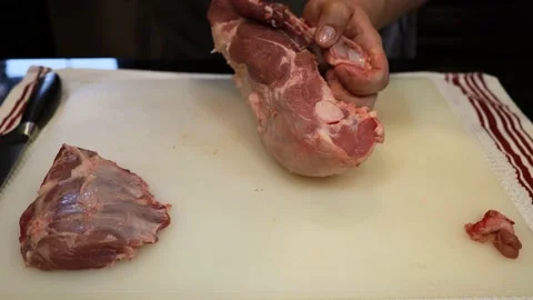 Man Cutting and trimming Large Pork Meat In A Kitchen With Two Knives Stock Footage 140556115