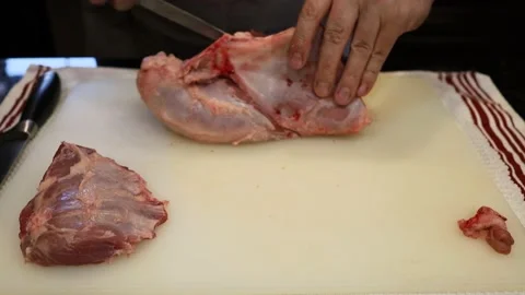 Man Cutting and trimming Large Pork Meat In A Kitchen With Two Knives Video stock 140556500