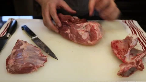 Man Cutting and trimming Large Pork Meat In A Kitchen With Two Knives Video stock 140556572