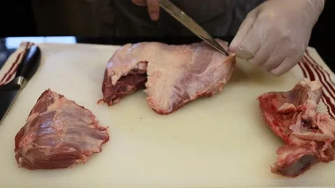 Man Cutting and trimming Large Pork Meat In A Kitchen With Two Knives Stock Footage 140557487