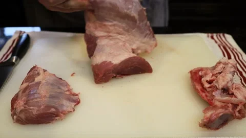 Man Cutting and trimming Large Pork Meat In A Kitchen With Two Knives Stock Footage 140557660