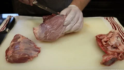 Man Cutting and trimming Large Pork Meat In A Kitchen With Two Knives Stock Footage 140557697