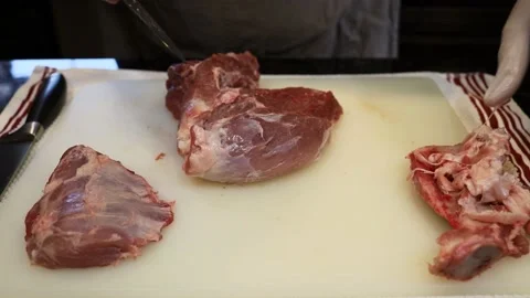 Man Cutting and trimming Large Pork Meat In A Kitchen With Two Knives Stock Footage 140557792