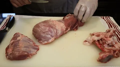 Man Cutting and trimming Large Pork Meat In A Kitchen With Two Knives Video stock 140558252