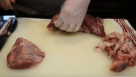 Man Cutting and trimming Large Pork Meat In A Kitchen With Two Knives Stock Footage 140558435